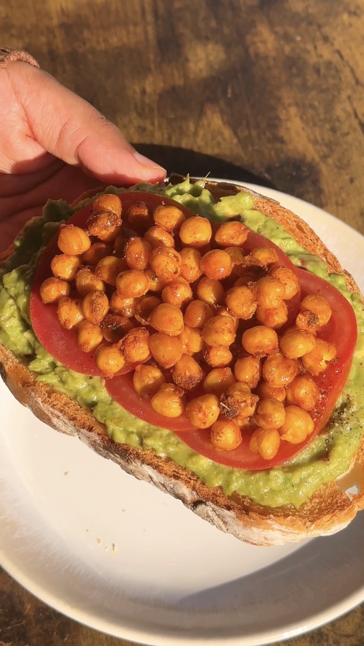 Cajun avocado toast topped with crispy chickpeas and a tomato slice on mashed avocado over sourdough bread